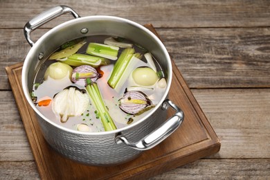 Different ingredients for cooking tasty bouillon in pot on wooden table, space for text