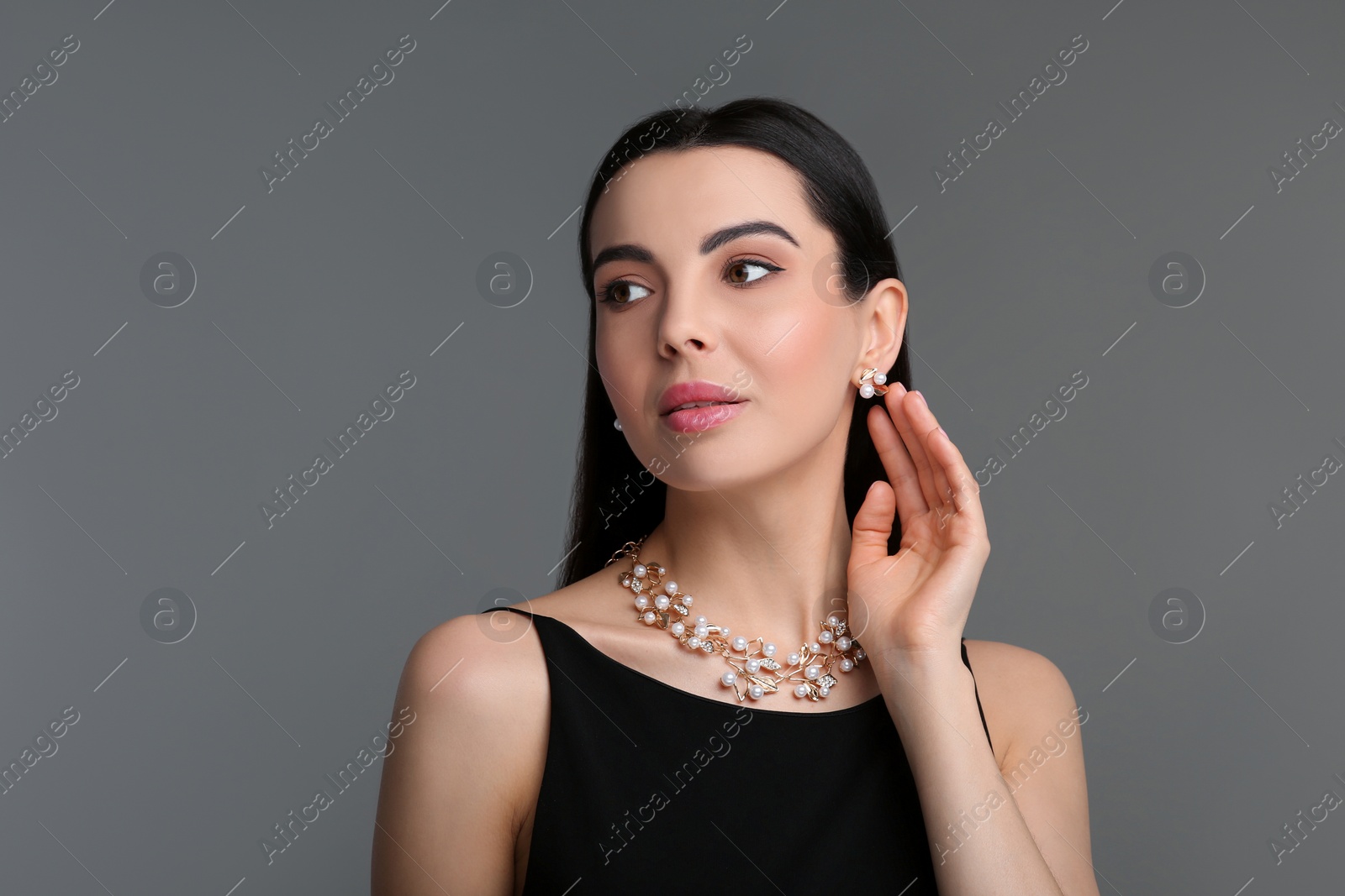 Photo of Beautiful young woman with elegant jewelry on dark grey background