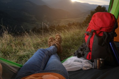 Photo of Woman resting inside of camping tent in mountains at sunset, closeup