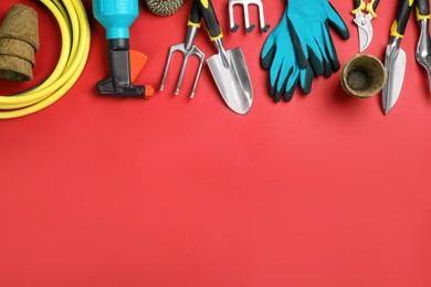 Flat lay composition with gardening tools on red background, space for text