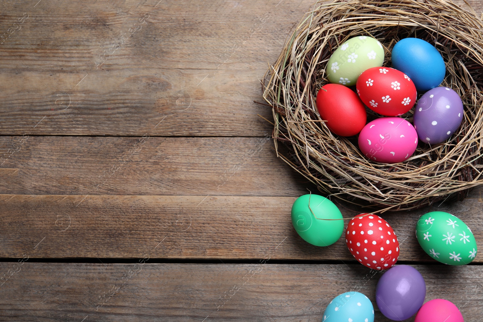 Photo of Colorful eggs and nest on wooden background, flat lay with space for text. Happy Easter