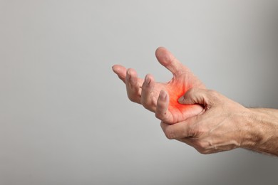 Image of Arthritis symptoms. Man suffering from pain in his hand on grey background, closeup. Space for text