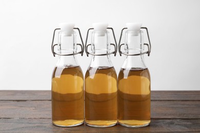 Photo of Homemade fermented kombucha in glass bottles on wooden table