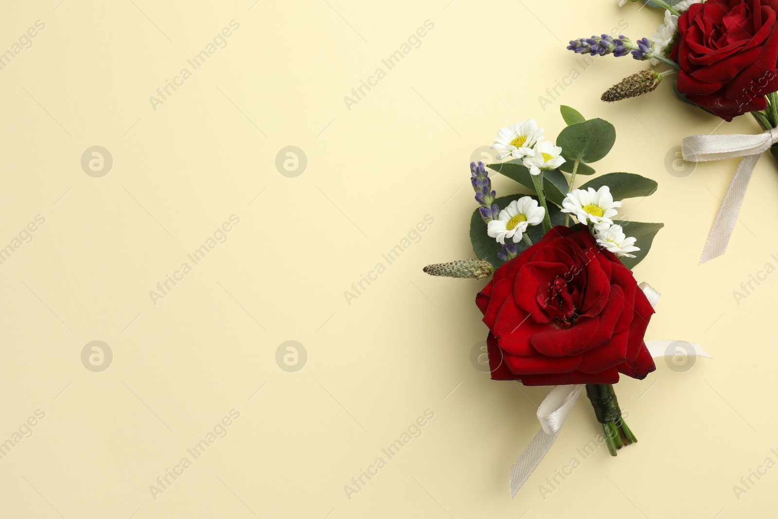 Photo of Stylish red boutonnieres on beige background, flat lay. Space for text