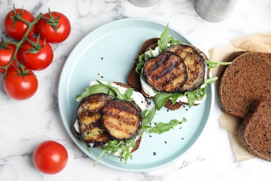 Delicious eggplant sandwiches served on white marble table, flat lay