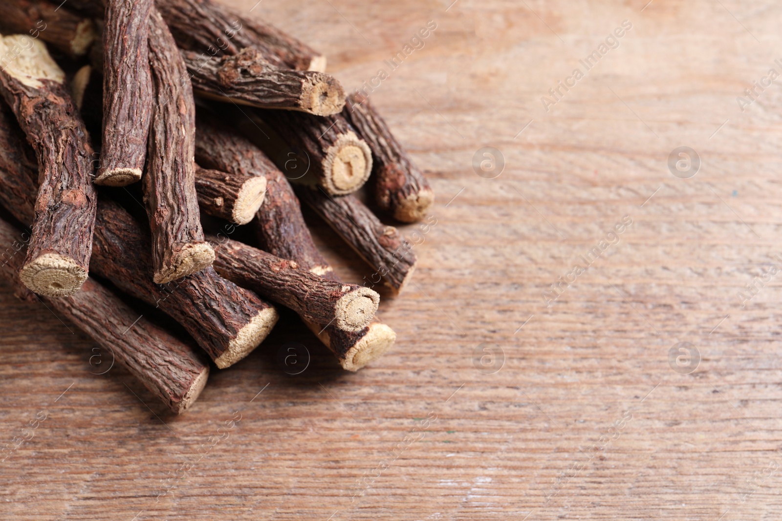 Photo of Dried sticks of liquorice root on wooden table, space for text