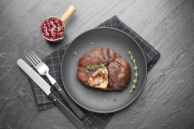 Delicious roasted beef meat served with sauce on black table, flat lay