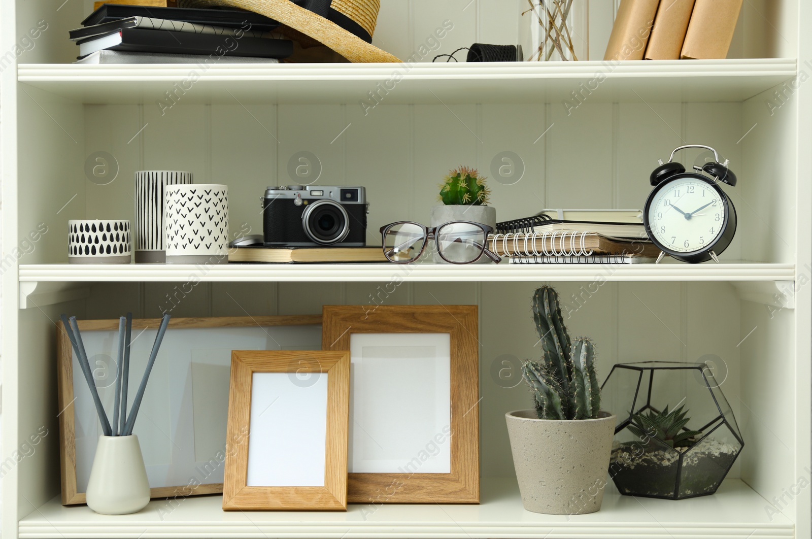 Photo of White shelving unit with photo frames and different decorative elements