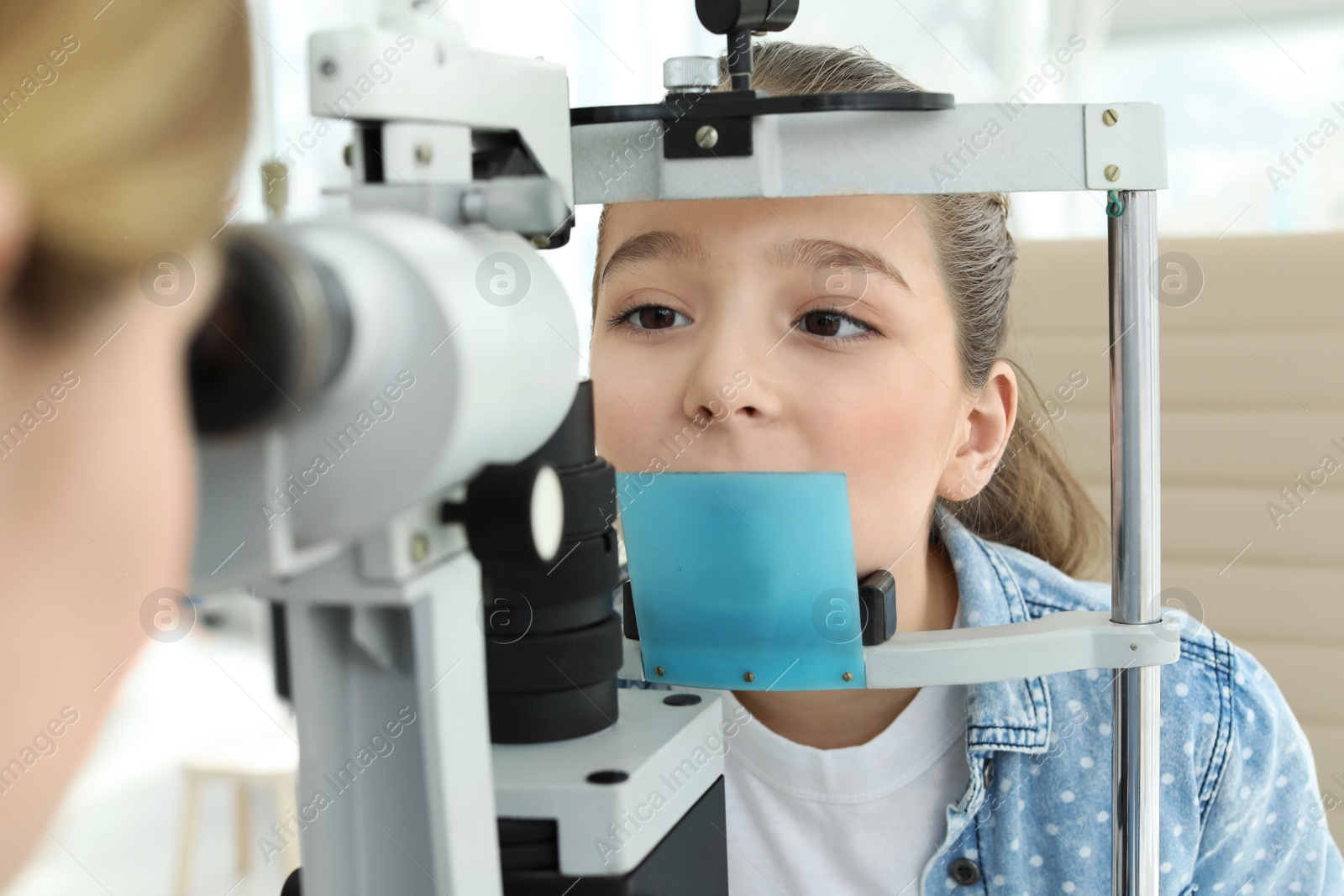 Photo of Ophthalmologist examining little girl in clinic