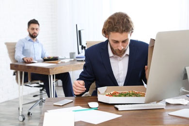 Photo of Office employee having pizza for lunch at workplace. Food delivery