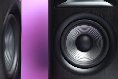 Photo of Wooden sound speakers on violet background, closeup