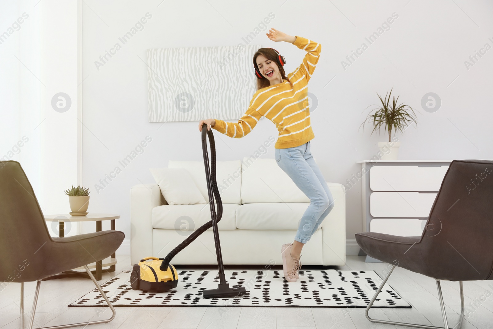 Photo of Young woman having fun while vacuuming at home