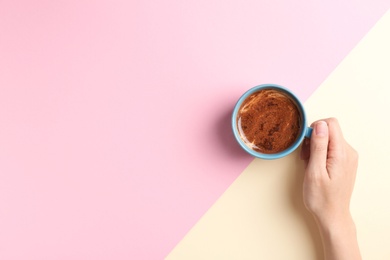 Photo of Young woman with cup of delicious hot coffee on color background, top view