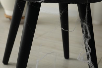 Photo of Old cobweb on chair in room, closeup