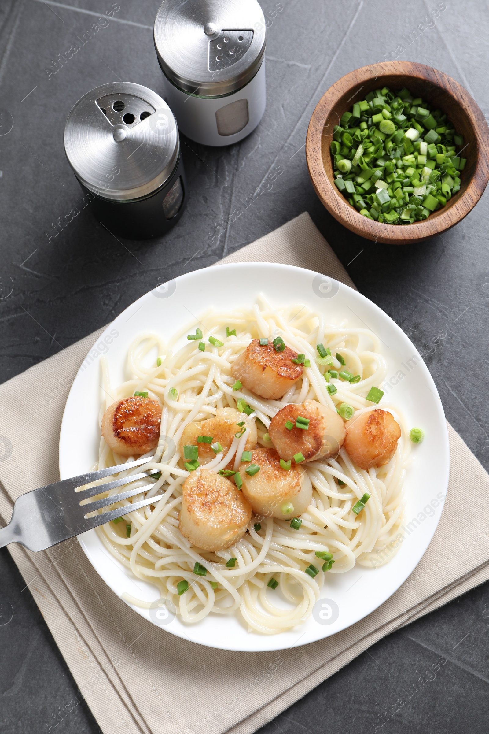 Photo of Delicious scallop pasta with green onion served on grey table, flat lay