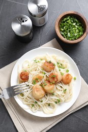 Delicious scallop pasta with green onion served on grey table, flat lay