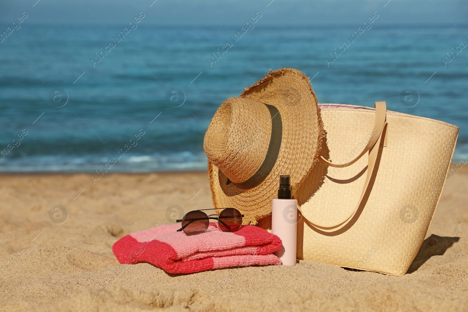 Photo of Straw hat, bag and other beach items on sandy seashore, space for text