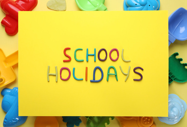 Flat lay composition with phrase School Holidays made of modeling clay on yellow background