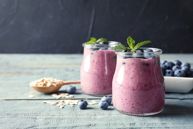 Photo of Tasty blueberry smoothie in jars, berries and oatmeal on wooden table