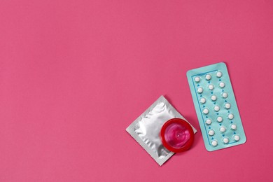 Photo of Contraception choice. Pills and condoms on magenta background, flat lay. Space for text