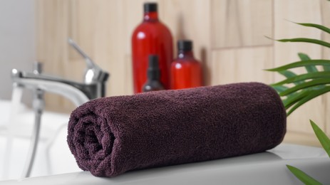 Rolled bath towel on tub in bathroom