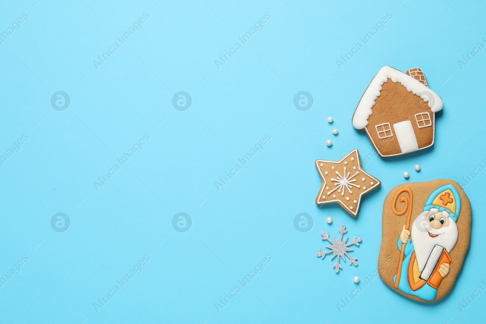 Photo of Tasty gingerbread cookies on light blue background, flat lay with space for text. St. Nicholas Day celebration