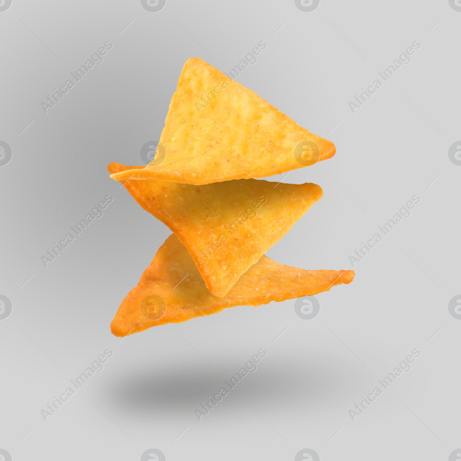 Image of Three tasty tortilla chips falling on grey background