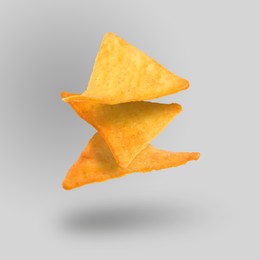 Three tasty tortilla chips falling on grey background