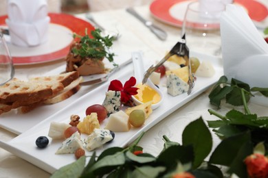 Photo of Plate with different types of cheeses and grapes on white table