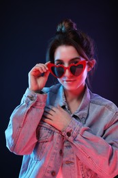 Portrait of young woman in sunglasses on color background
