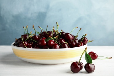 Plate with sweet red cherries on wooden table