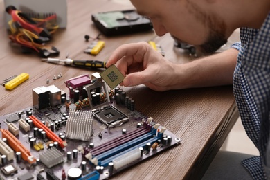 Male technician repairing motherboard at table, closeup