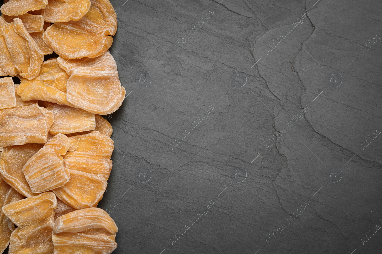 Photo of Delicious dried jackfruit slices on black table, flat lay. Space for text