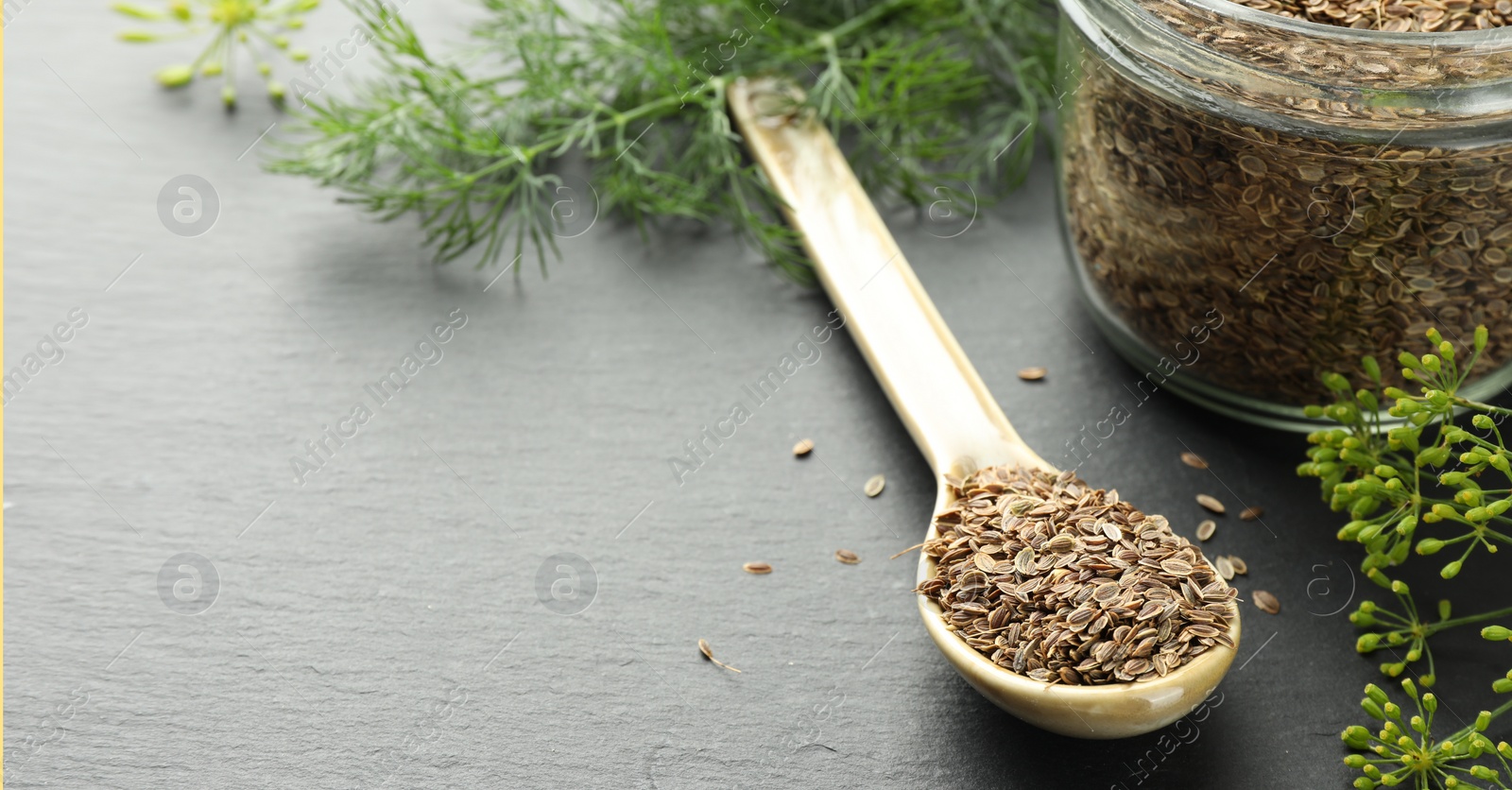 Image of Dill seeds in spoon and jar on grey table. Banner design with space for text