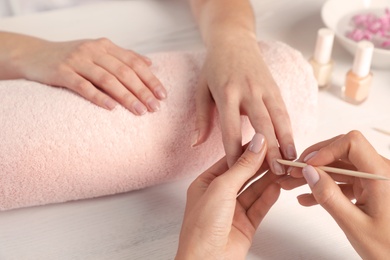 Photo of Manicurist filing client's nails at table, closeup. Spa treatment