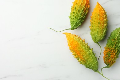 Photo of Beautiful bitter melons on white marble table, flat lay. Space for text