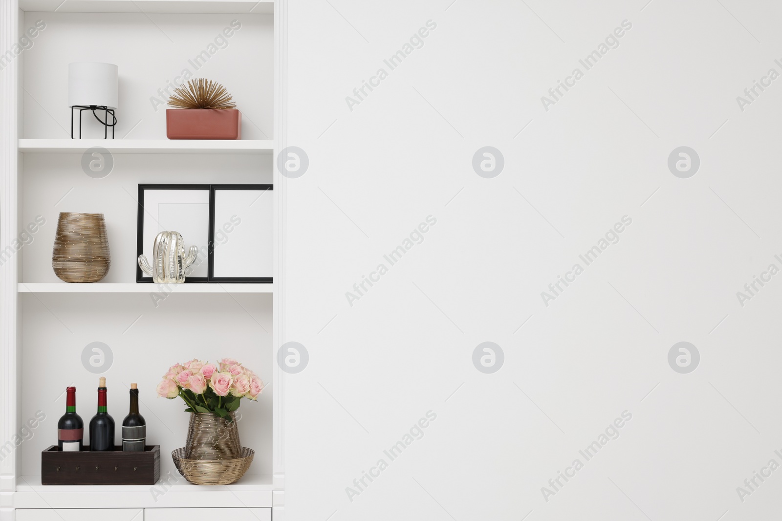 Photo of Shelves with different decor near white wall, space for text. Interior design