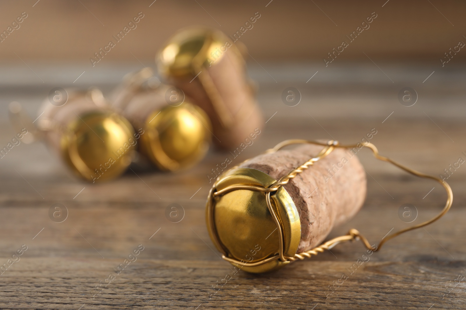 Photo of Cork of sparkling wine and muselet cap on wooden table, closeup. Space for text
