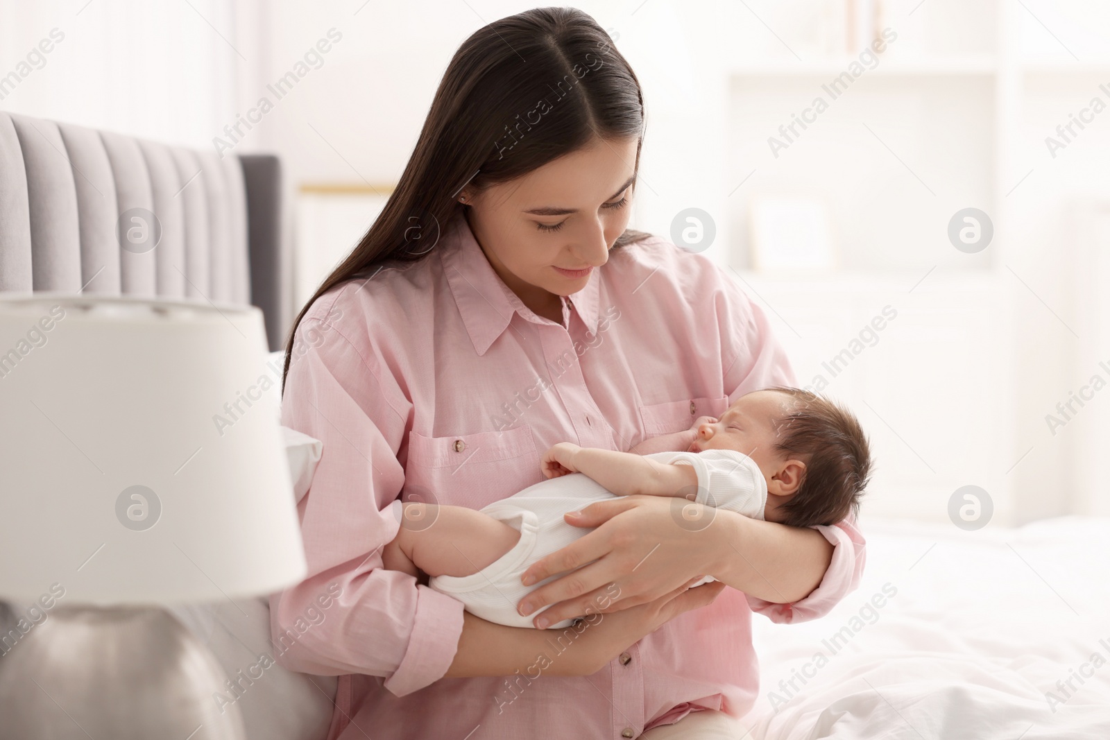 Photo of Mother with her sleeping newborn baby on bed at home