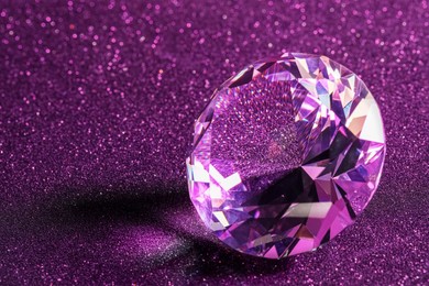 Photo of Beautiful shiny diamond on purple glitter background, closeup. Space for text