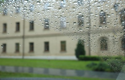 Photo of Blurred view of city street through wet car window. Rainy weather