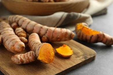 Many raw turmeric roots on grey table, closeup