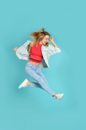 Full length portrait of emotional woman jumping on color background