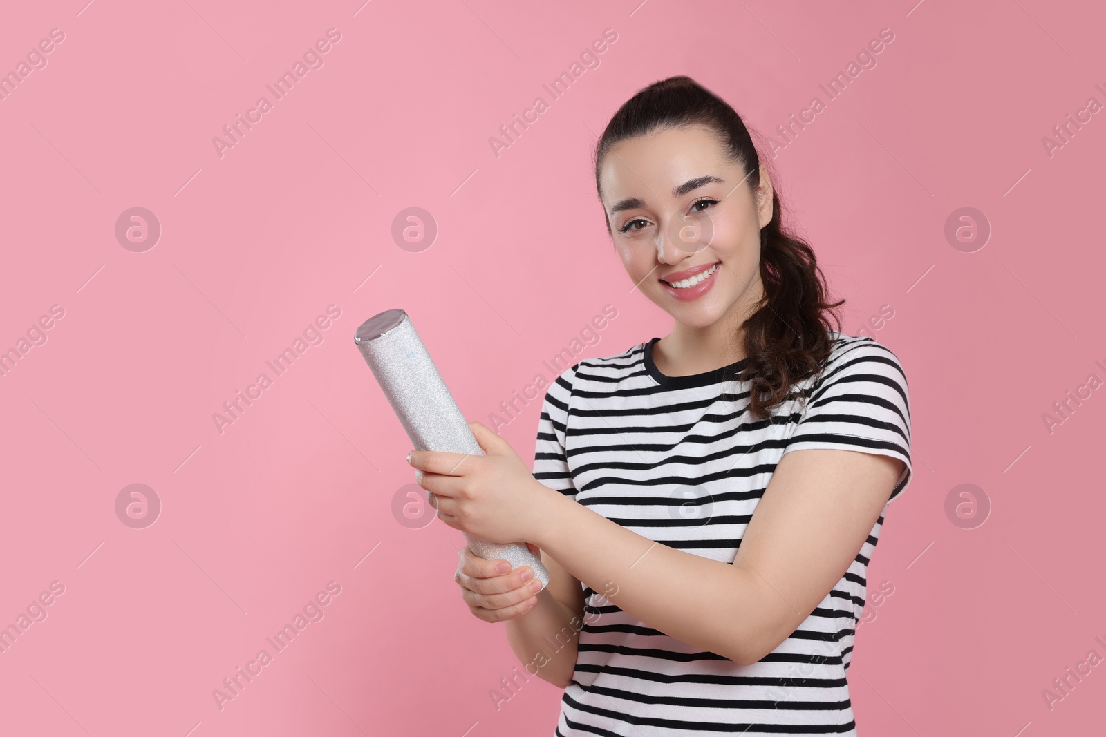 Photo of Young woman blowing up party popper on pink background