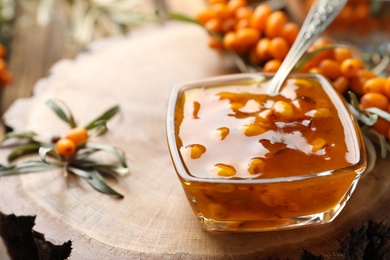 Delicious sea buckthorn jam and fresh berries on wood, closeup. Space for text