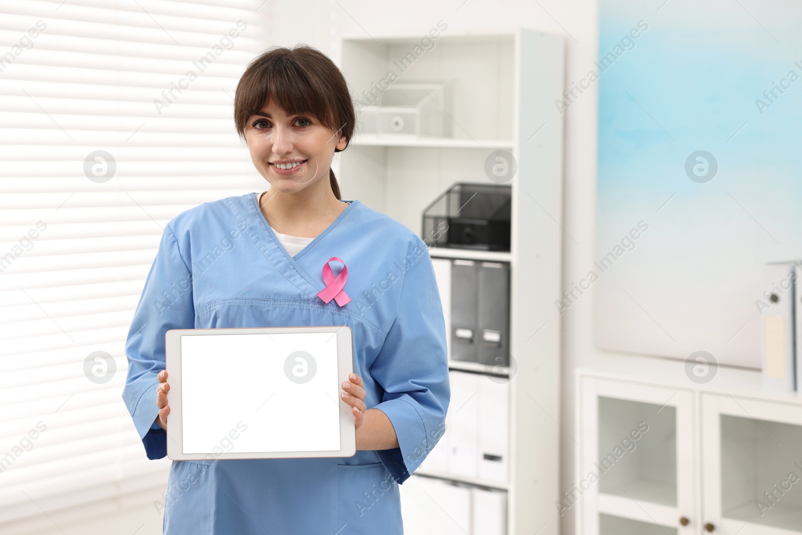 Photo of Mammologist with pink ribbon showing tablet in hospital, space for text. Breast cancer awareness