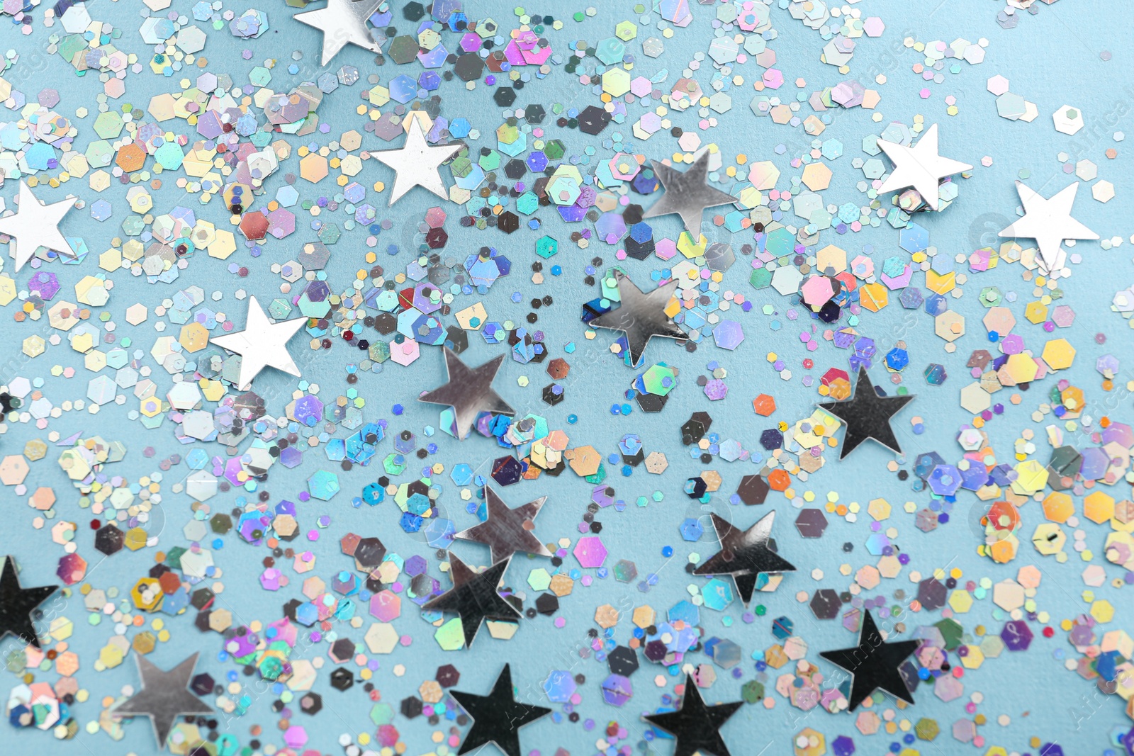 Photo of Shiny glitter on light blue background, above view