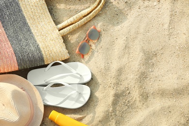 Composition with beach accessories on sand, flat lay. Space for text