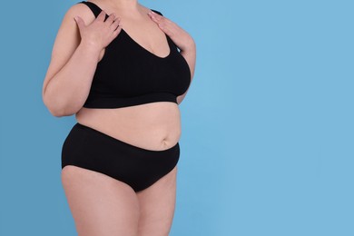 Photo of Overweight woman in underwear on light blue background, closeup. Space for text