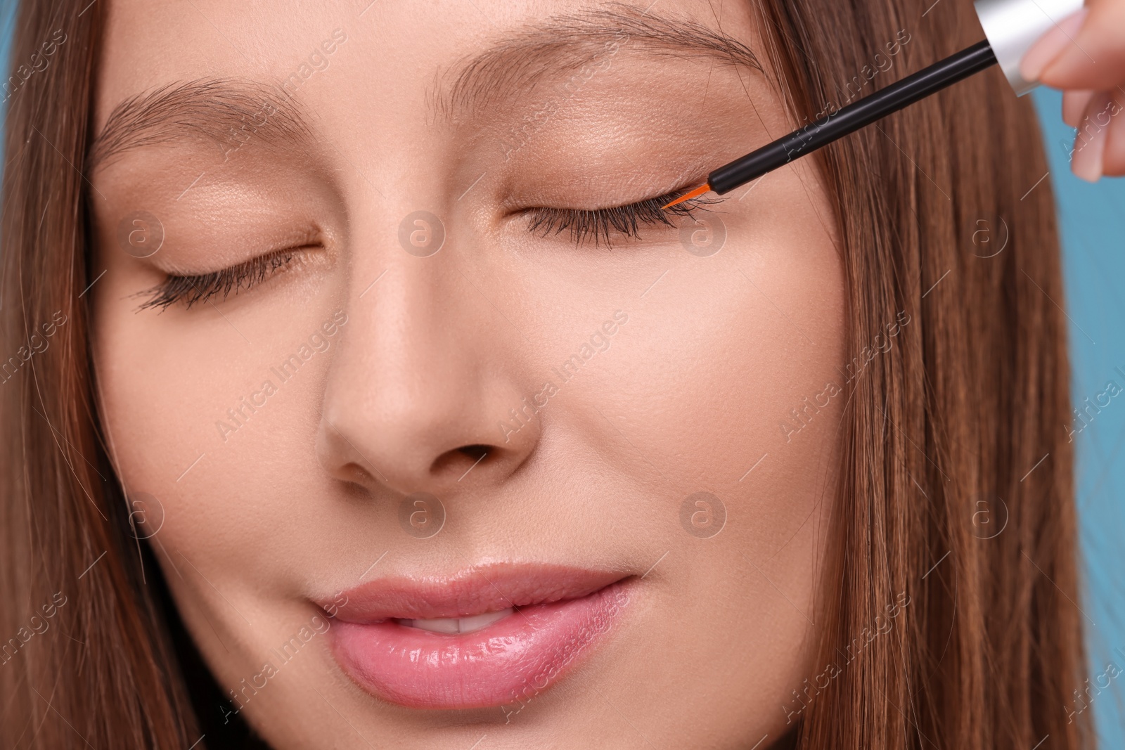 Photo of Beautiful woman applying serum onto eyelashes, closeup